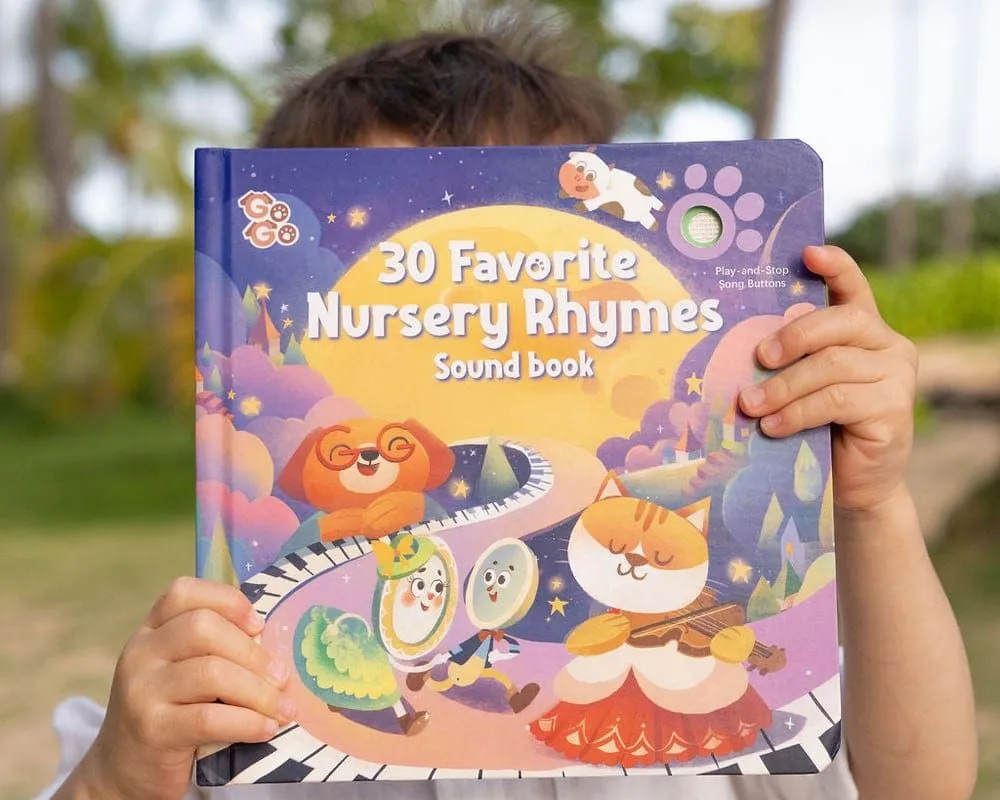 A child holding up the 30 Favorite Nursery Rhymes sound book